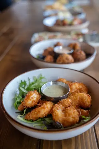 Coconut shrimp with dipping sauce over greens