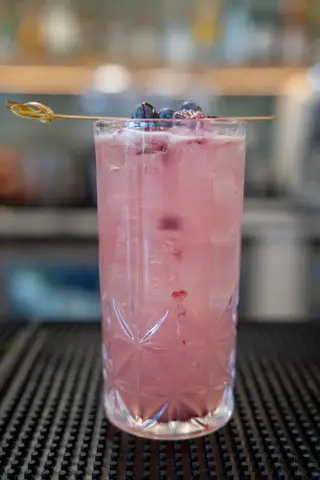 Tall pink blueberry cocktail on the bar
