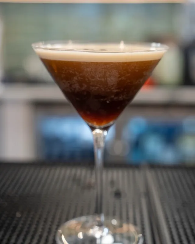 Espresso martini with a crema head, served up on the bar rail